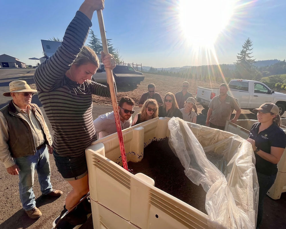 A tour group watching a winemaker perform a Pinot Noir punchdown during a behind-the-scenes Willamette Valley wine tour.