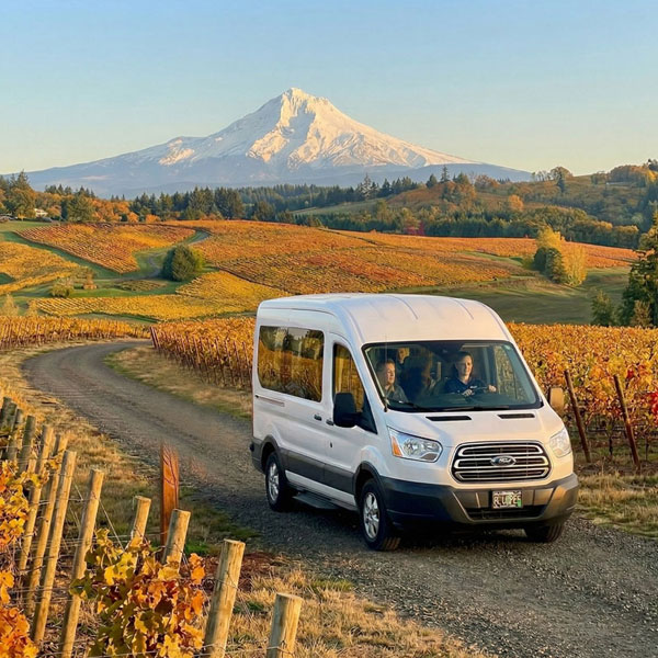 Private wine tour vehicle driving through Oregon wine country with Mount Hood in the background