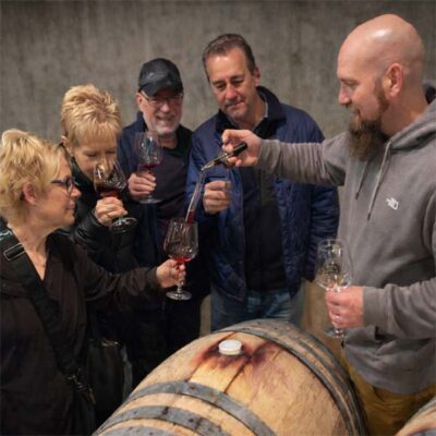 Guests gathered around a barrel during a private Willamette Valley wine tasting
